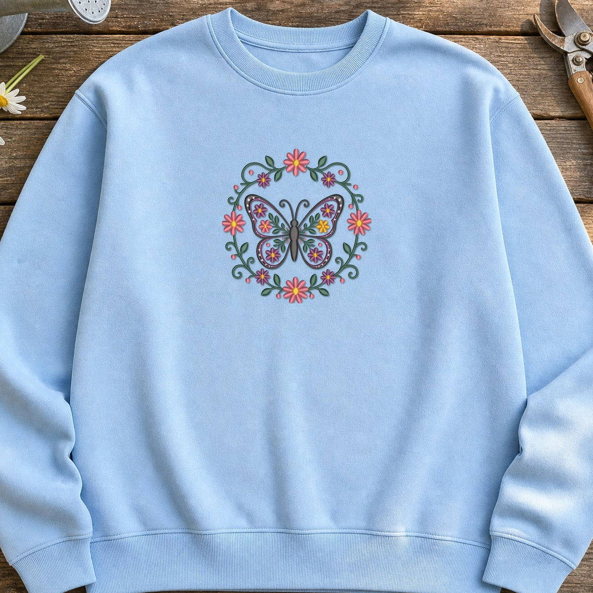 Butterfly Circle Flowers embroidery design stitched on a light sky blue relaxed cotton crewneck sweatshirt