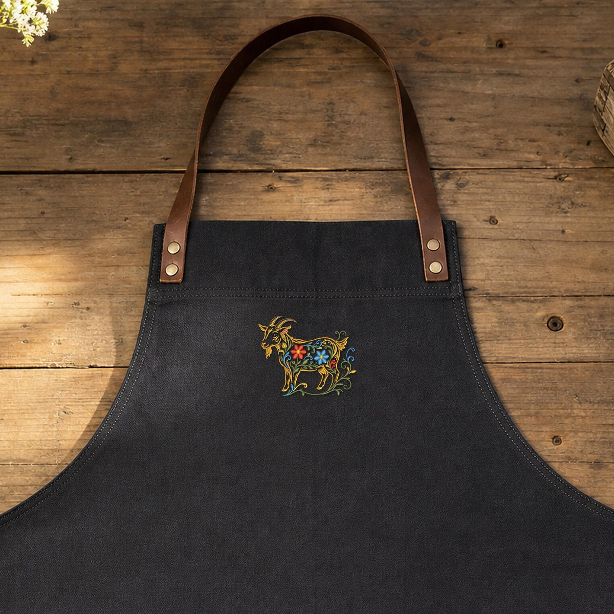 Goat Filled Flowers embroidery design stitched on a charcoal heavy-duty canvas kitchen apron