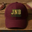 JNB Puff Cap embroidery design stitched on a deep burgundy structured six-panel baseball cap
