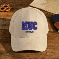 MUC Puff Cap embroidery design stitched on a heather oatmeal structured baseball cap