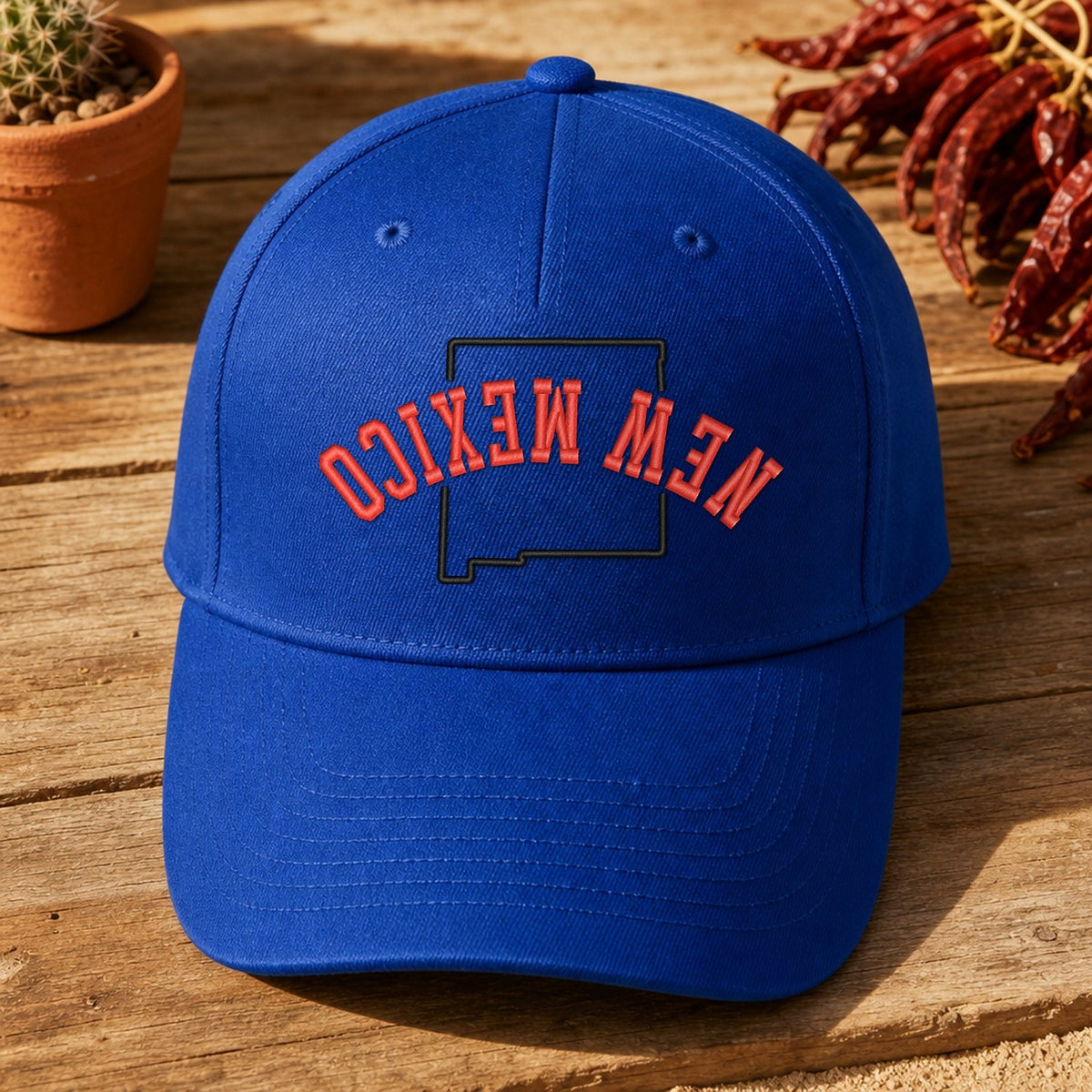 New Mexico State Upside Down embroidery design stitched on a royal blue structured six-panel baseball cap
