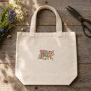 Pig Filled Flowers embroidery design stitched on a 15-inch natural unbleached canvas market tote bag