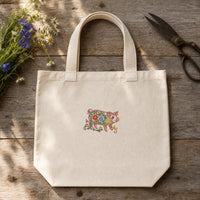 Pig Filled Flowers embroidery design stitched on a 15-inch natural unbleached canvas market tote bag