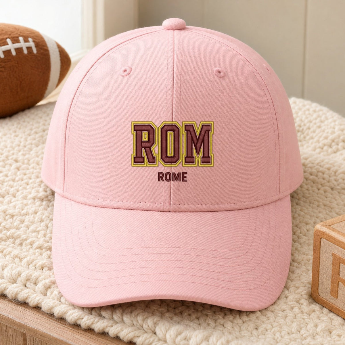 ROM Puff Cap embroidery design stitched on a soft pastel pink structured six-panel baseball cap