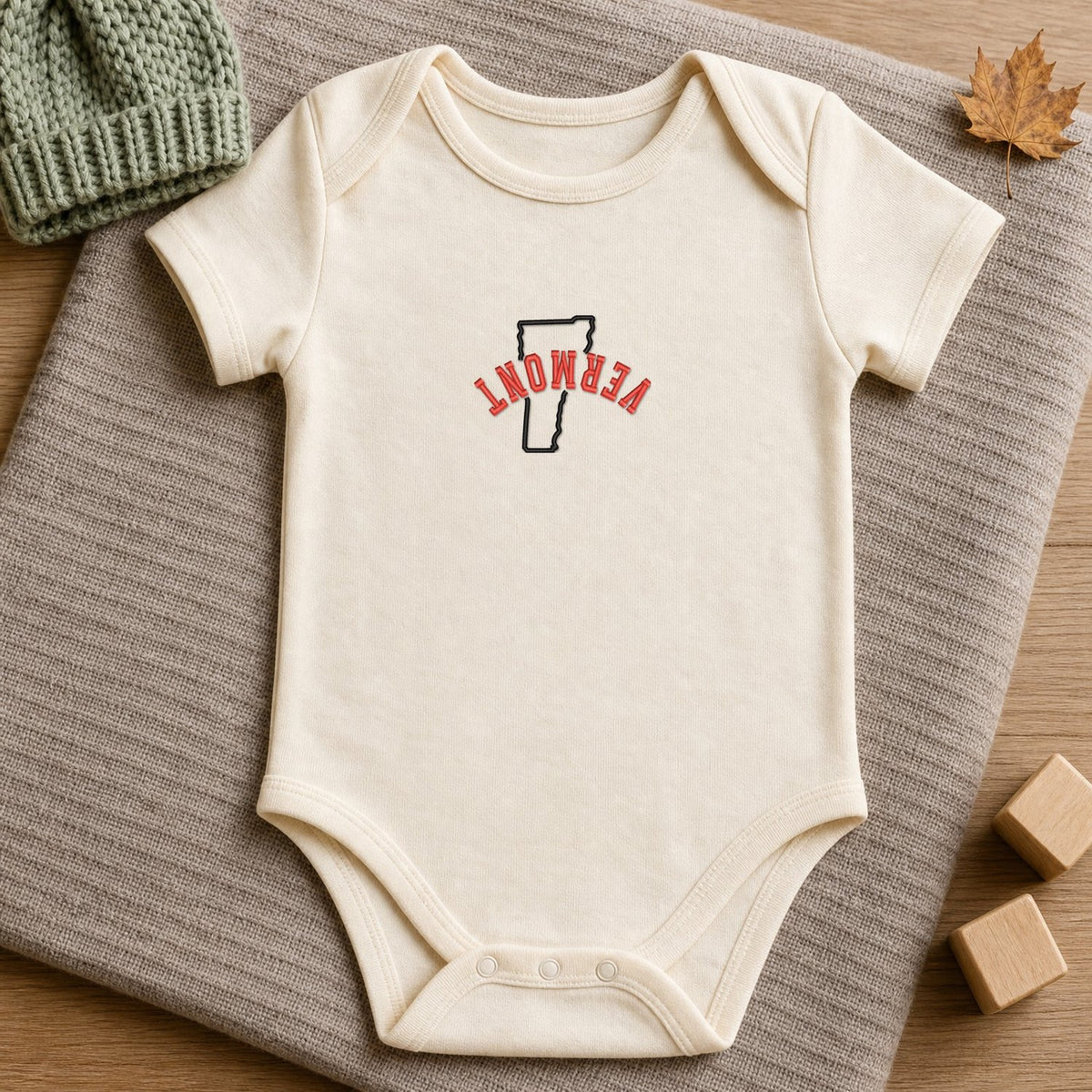 Vermont State Upside Down embroidery design stitched on a soft natural organic cotton baby onesie