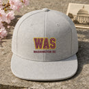 WAS Puff Cap embroidery design stitched on a light heather grey structured 6-panel snapback cap